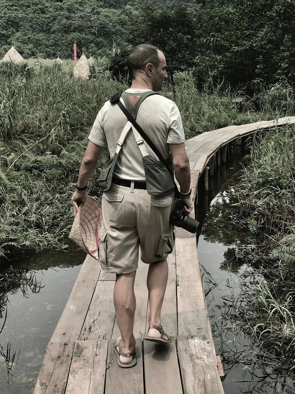 Aventurero con su bolso Movers Bag puesto pasando por una pasarela de madera en Vietnam