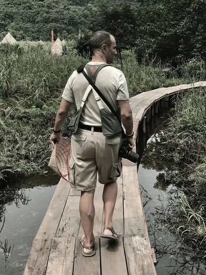 Aventurero con su bolso Movers Bag puesto pasando por una pasarela de madera en Vietnam
