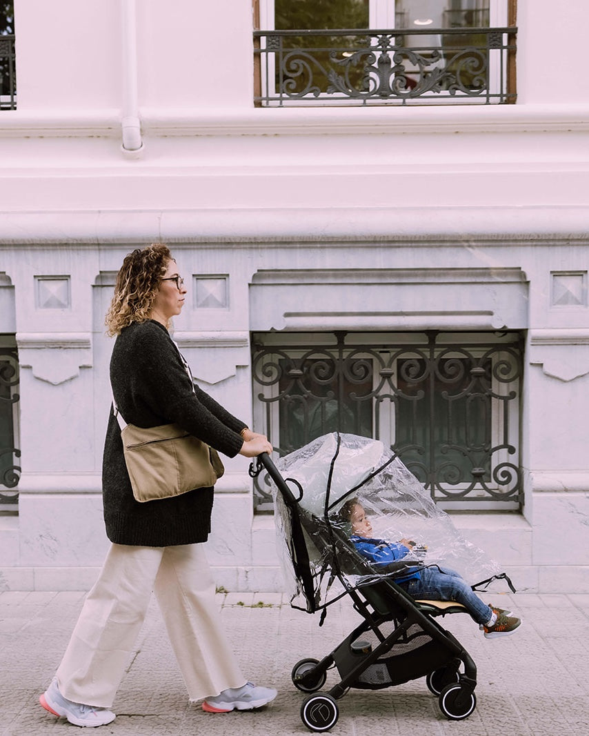 Mujer paseando con un carrito de bebé y un Movers Bag beige puesto