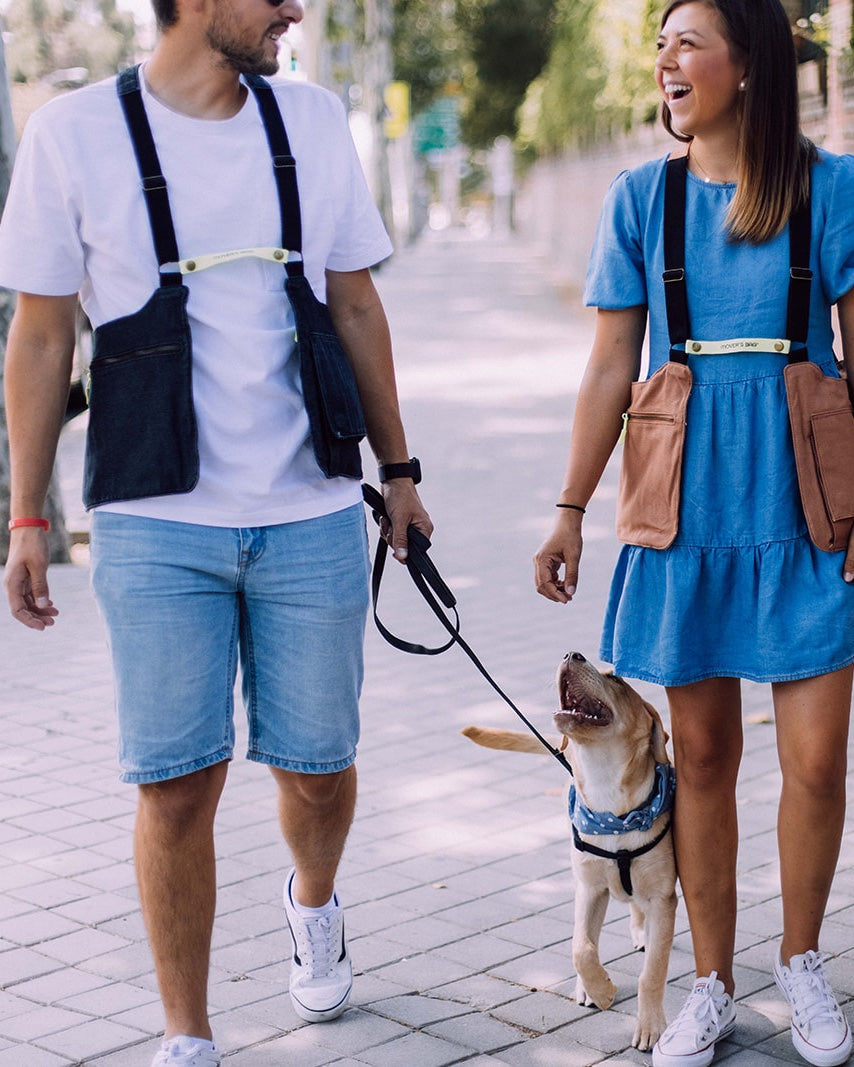 Pareja paseando a su perro por la ciudad, cada uno con su Movers Bag puesto